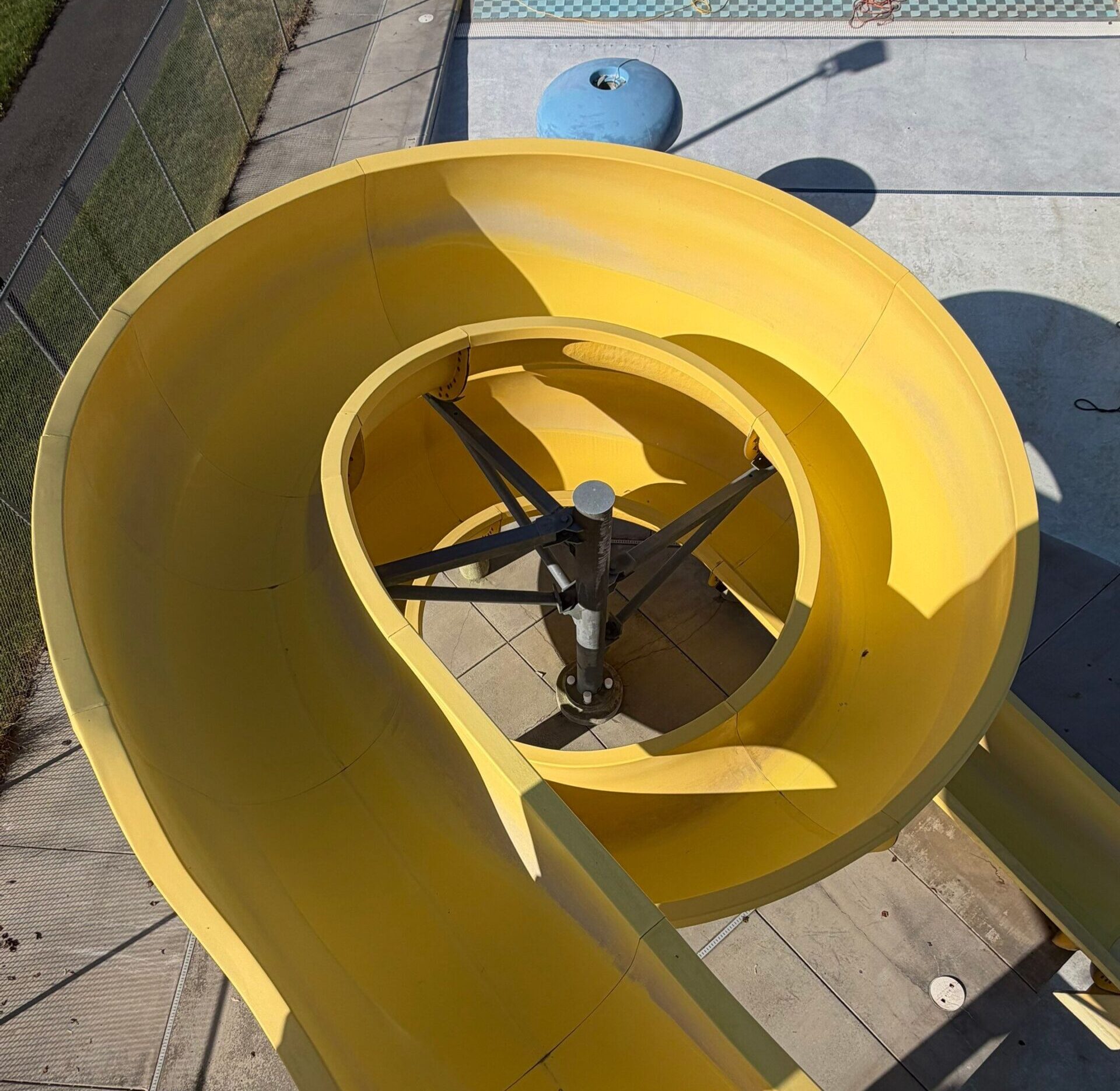 Before restoration overhead view of faded yellow open flume body slide at Ritzville Waterpark